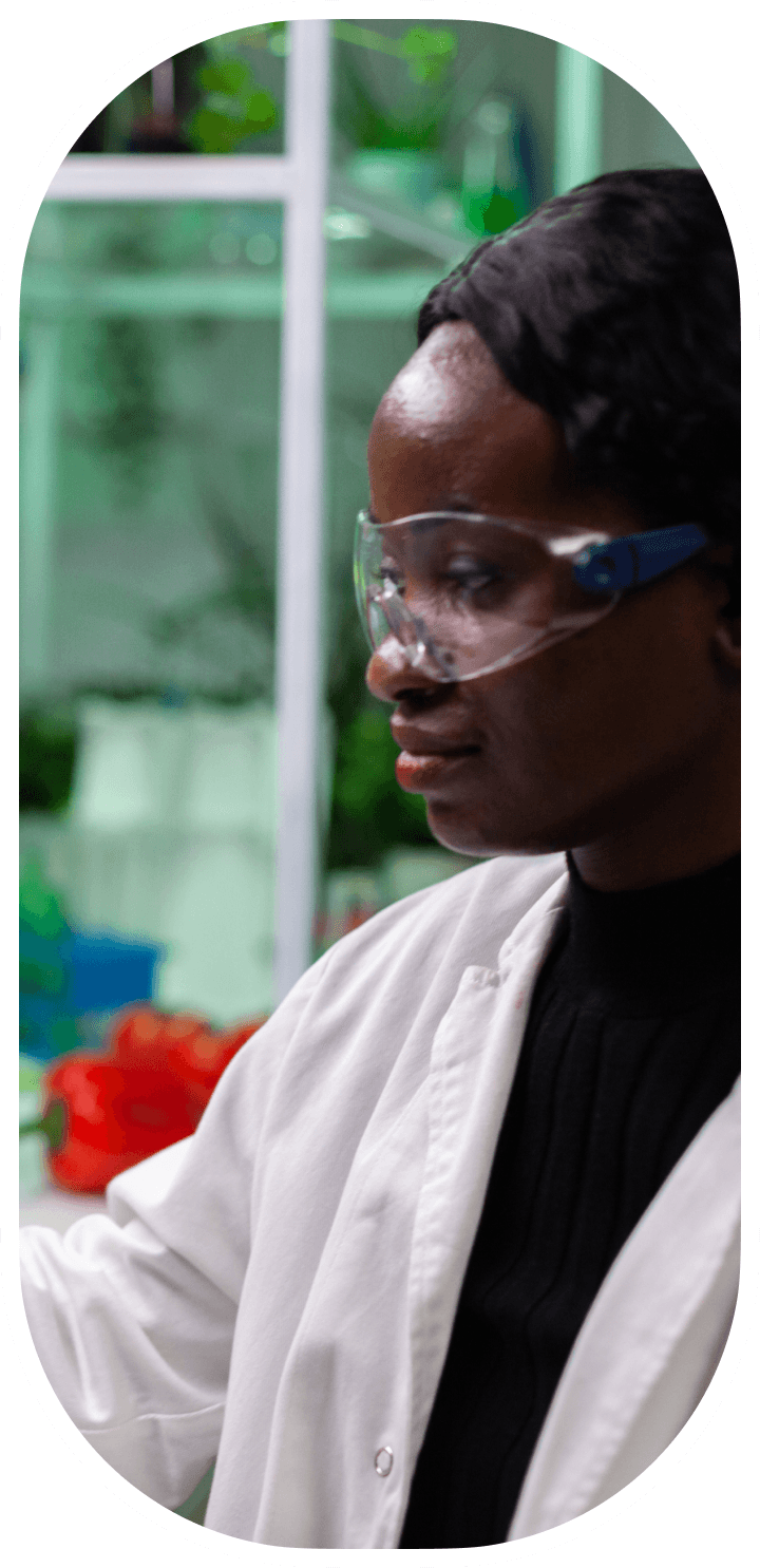Researcher in safety glasses working in a plant lab